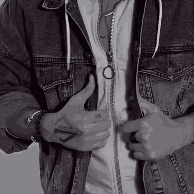 a man wearing a denim jacket is giving a thumbs up sign
