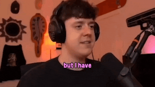 a man wearing headphones is standing in front of a microphone and saying `` but i have '' .