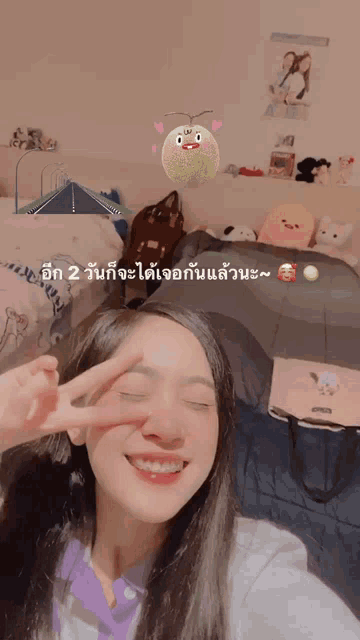 a girl giving a peace sign in front of a bed with stuffed animals on it