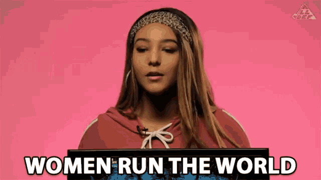 a woman in a red hoodie is holding a sign that says women run the world