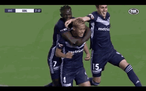a group of soccer players are hugging each other on a field .