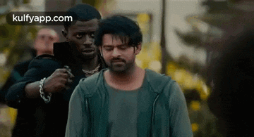 a man is standing next to another man with a gun on his shoulder .
