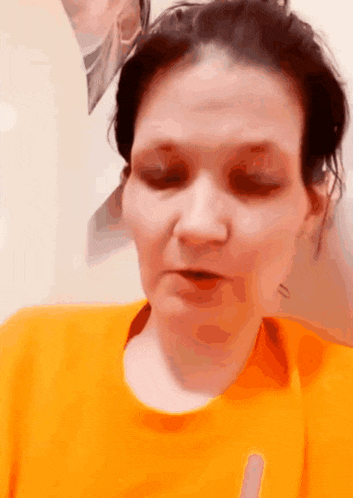 a woman is wearing an orange shirt and making a face .