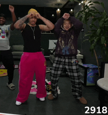 a man in a black tank top and pink sweatpants is dancing with another man in a purple hoodie and plaid pants