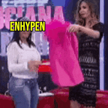 two women are standing next to each other and one of them is holding a pink dress .
