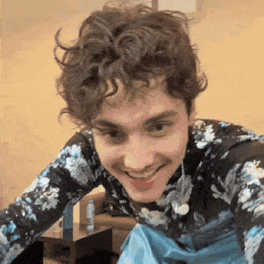 a young man with curly hair is smiling for the camera
