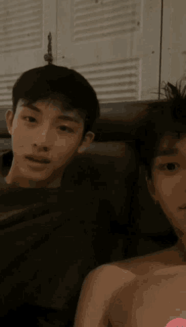 a man without a shirt is sitting on a couch with another man