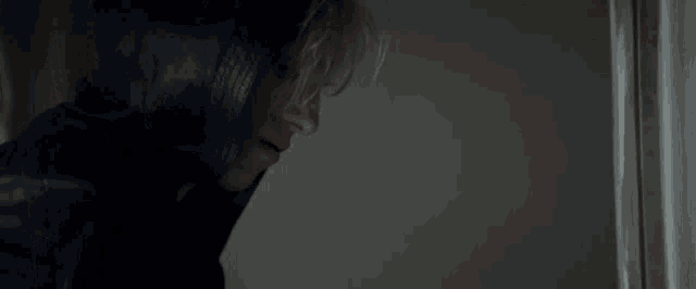 a woman in a black hoodie is standing in a dark room .