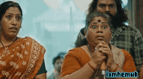 a woman with a surprised look on her face is next to a man and a sign that says iamhemuk