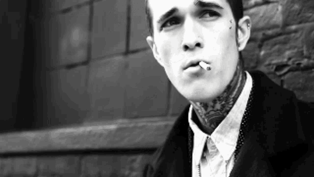 a young man with a tattoo on his neck is smoking a cigarette .