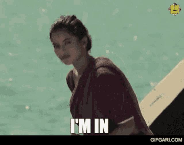 a woman is standing in front of a body of water and says `` i 'm in '' .