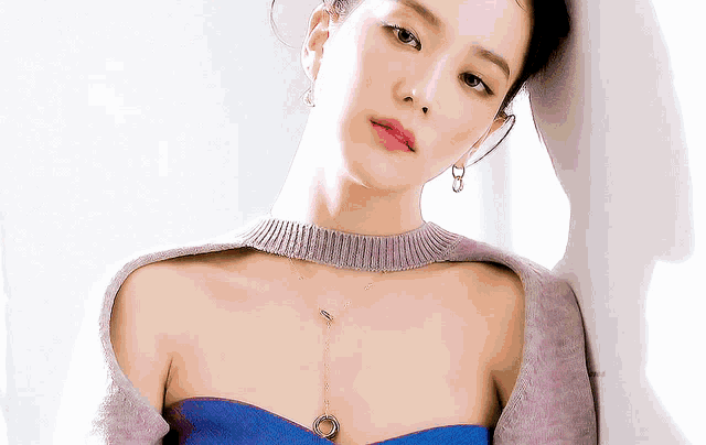 a woman wearing a choker necklace and earrings is leaning against a wall