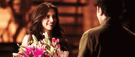 a woman is smiling while holding a bouquet of flowers in front of a man .