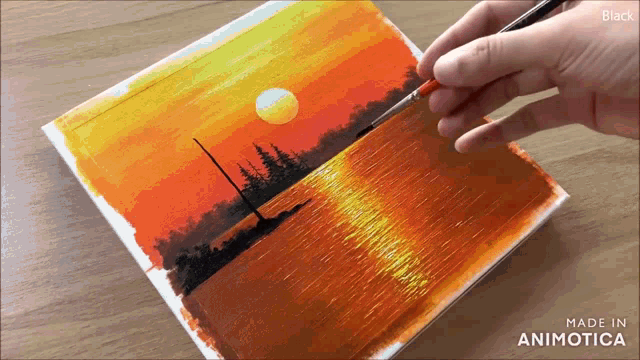 a person is painting a sunset over the ocean