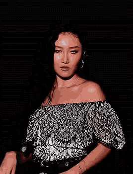 a woman is holding a microphone and smiling while wearing a off the shoulder top .