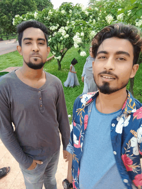 two men posing for a picture in front of a tree