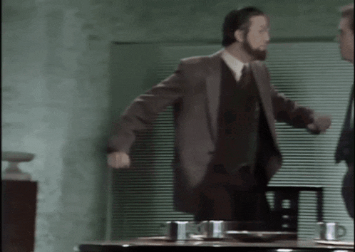 a man in a suit stands in front of a table