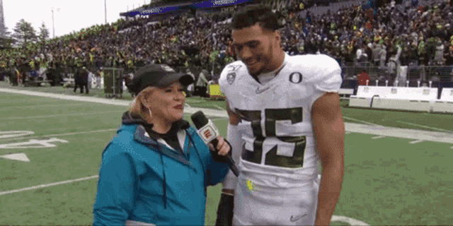 a woman is interviewing a football player wearing a jersey with the number 52 on it