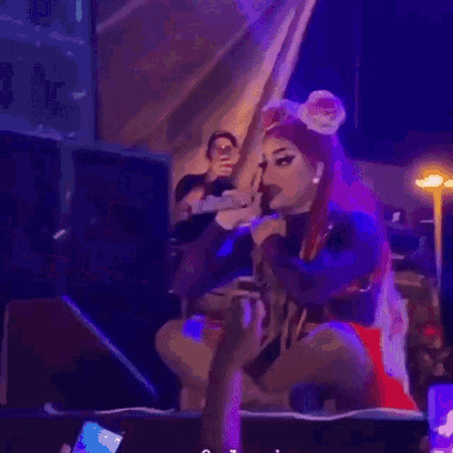 a woman with red hair is sitting on a stage in front of a microphone