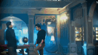 two men are standing in a room with a globe in the middle of the room .
