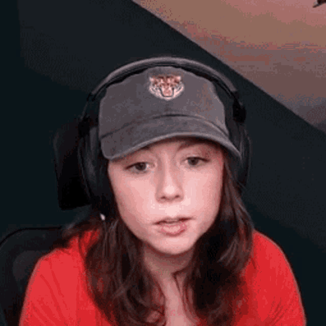 a young girl wearing a hat and headphones is sitting in front of a computer screen .