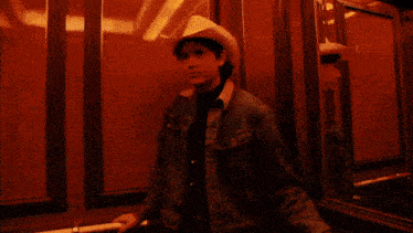 a man wearing a cowboy hat is standing in front of a wall that has the letters wvw written on it