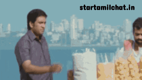 two men are standing in front of a city and the website starttamilchat.in is visible