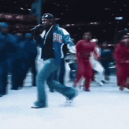 a man is singing into a microphone while a group of people dance