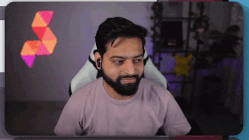 a man with a beard is sitting in a chair looking at the camera