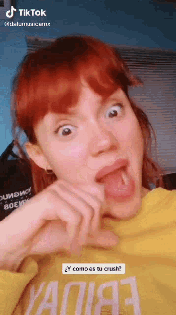 a woman with red hair is wearing a yellow shirt that says ' y como es tu crush ? '