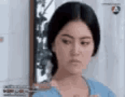 a woman in a blue shirt is looking at the camera and making a funny face .