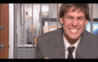 a man in a suit and tie is smiling and making a funny face behind bars .