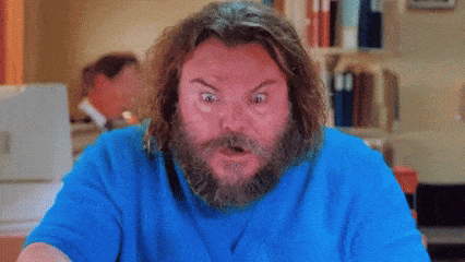 a man with a beard is wearing a blue shirt and making a surprised face