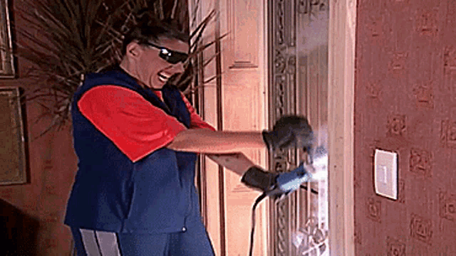 a man wearing goggles and gloves is welding a door with a drill .