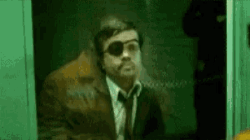 a man in a suit and tie is wearing sunglasses and a blindfold .