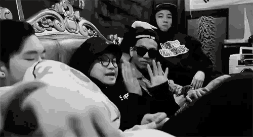 a black and white photo of a group of people sitting on a bed .