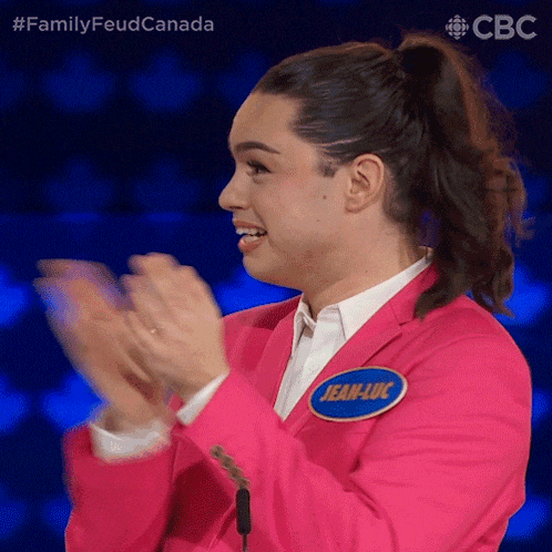 a woman in a pink suit with a name tag that says jean-luc applauds