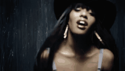 a woman wearing a hat and earrings is singing into the camera