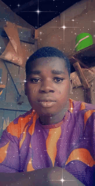 a young man in a purple and orange shirt looks at the camera with a tear coming out of his eye