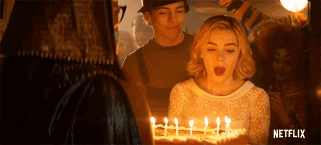 a woman blowing out candles on a birthday cake with a netflix logo in the corner