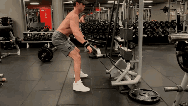 a shirtless man is doing exercises in a gym with a sign that says ' exit '