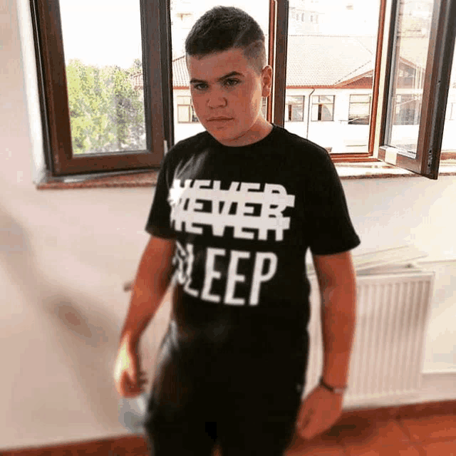 a boy wearing a shirt that says " never sleep "