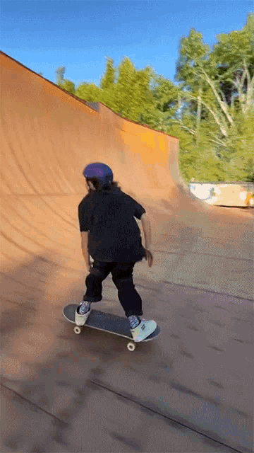 a person wearing a purple helmet rides a skateboard down a ramp