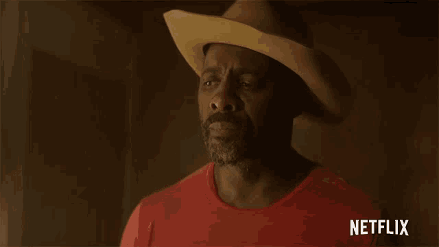 a man wearing a cowboy hat and a red shirt with a netflix logo on the bottom