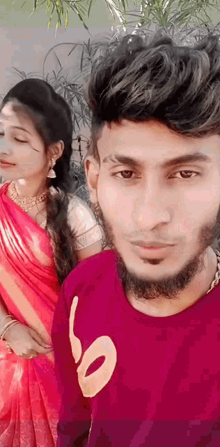 a man with a beard is posing for a picture with a woman in a red sari .