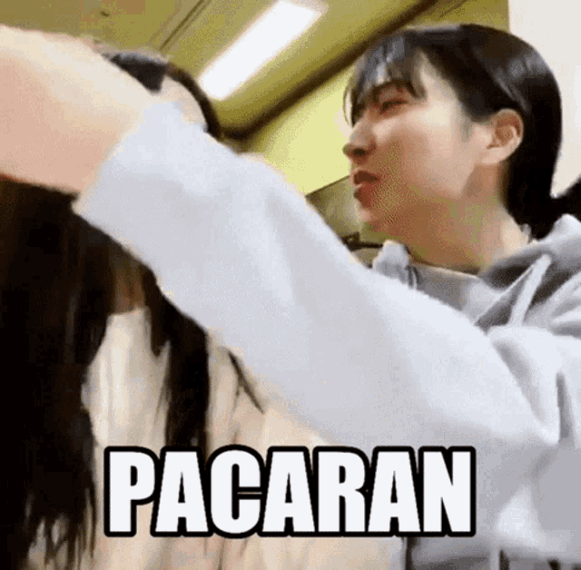 a woman is holding another woman 's hair with the word pacaran written on the bottom