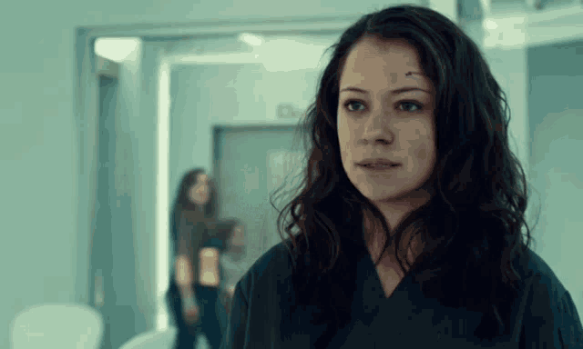a woman in a blue scrub is standing in a hallway looking at the camera