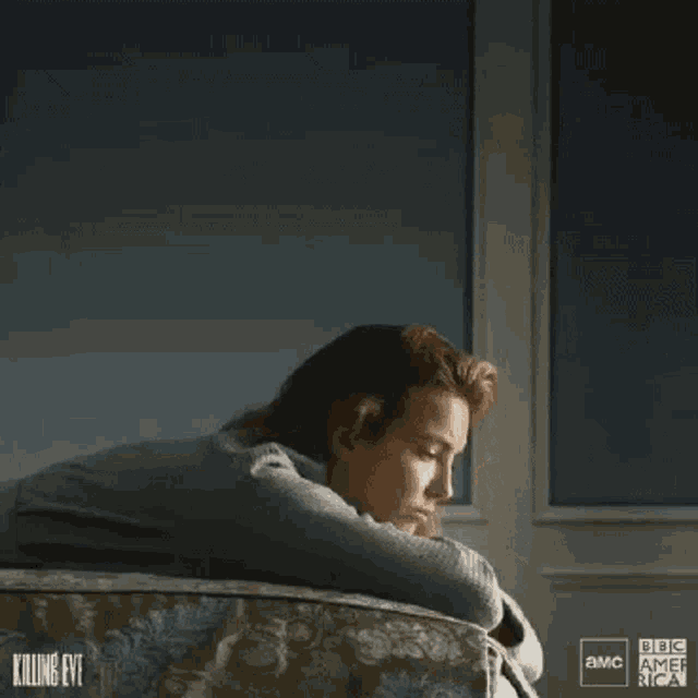 a woman is laying on her stomach on a bed with her hand on her face .