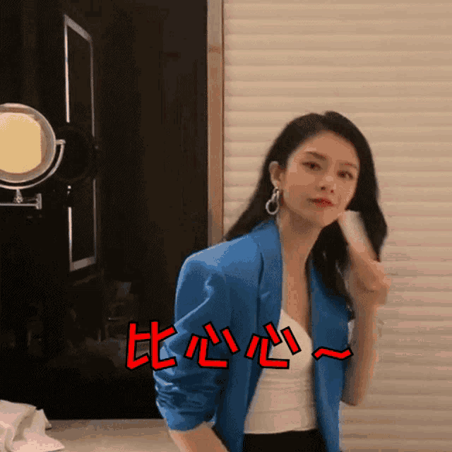 a woman in a blue jacket is standing in front of a mirror with chinese writing on the wall