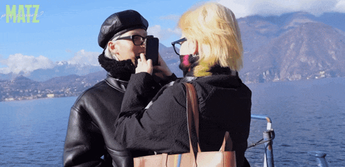 a woman taking a picture of another woman with the word matz in the upper right corner